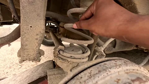 Mechanic hand inspecting rusty and dusty rear coil spring suspension of Stock Footage 343408674