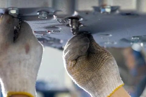 Mechanic hand installs threaded drain plug into transmission oil pan in rep.. Stock Photos