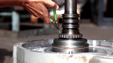 Mechanic hand using green pliers on machine shaft component. Stockbeeldmateriaal 340977990