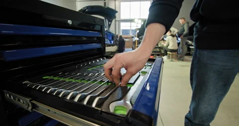 A mechanic handling tools and working on an electric car in a well-lit auto Stock Footage 277266349