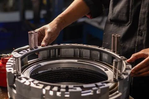 Mechanic hands assembling transmission clutch return spring assembly. Stock Photos