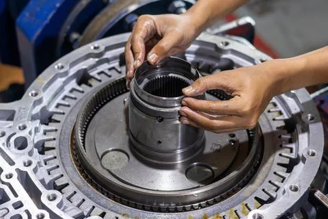 Mechanic hands assembling transmission hub component in workshop. Stock Photos
