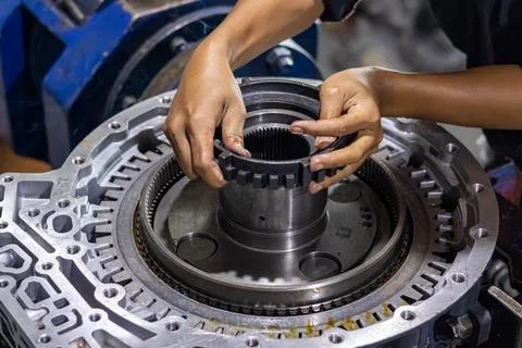 Mechanic hands assembling transmission splined gear hub in workshop. Stock Photos