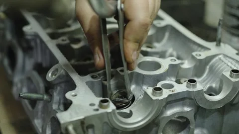 Mechanic hands compressing valve spring with tool inside cylinder head Stock Footage 340273786