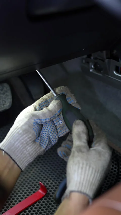 Mechanic hands in gloves using screwdriver under a car dashboard. 動画素材 344362472