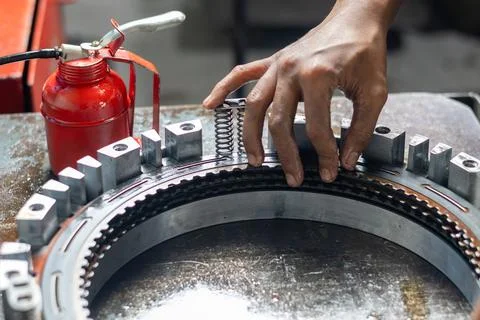 Mechanic hands installing clutch pack return spring on workbench. Foto stock