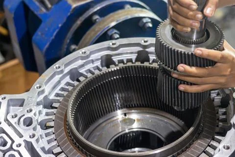 Mechanic hands installing planetary gear shaft into transmission drum in wo.. Stock Photos