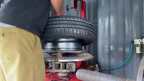 Mechanic inflating tyre on wheel in workshop Stock Footage 166457435