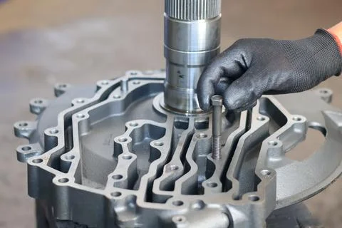 Mechanic inserting a bolt into a transmission front support. Stock Photos