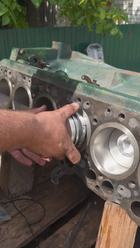 Mechanic inserting piston into engine cylinder block during overhaul Stock Footage 338411004