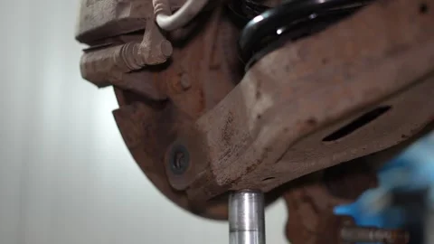 Mechanic inserts a greased alignment bolt into rear suspension arm. Stock Footage 345912616