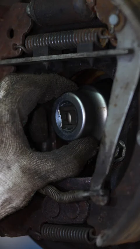 Mechanic inserts a metal socket tool into car brake drum. Stock Footage 344230588