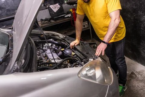 Mechanic inspecting car engine in workshop Stock Photos