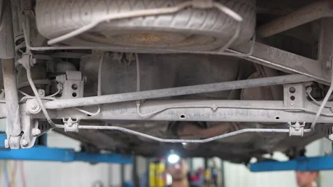 Mechanic Inspecting Car Suspension Control Arms Underneath Vehicle Stock Footage 345570338