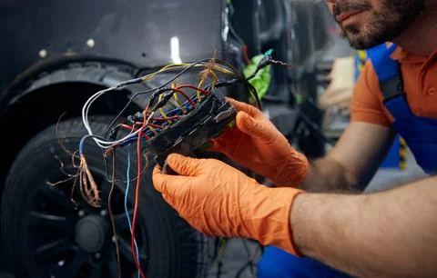 Mechanic inspecting complex car wiring harness in garage Stock Photos
