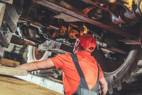 Mechanic Inspecting Heavy Machinery Components in a Workshop During Dayligh.. Photos