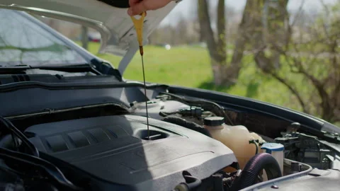Mechanic inspecting vehicle engine components at open car hood, utilizing Stock Footage 312517827