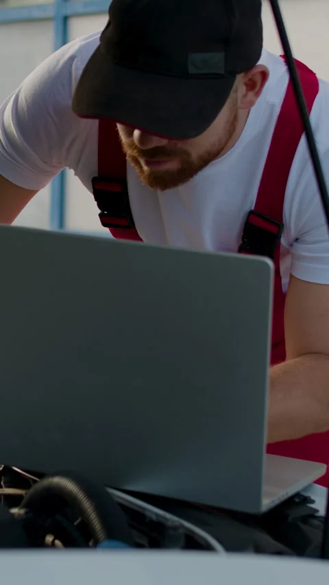 Mechanic inspecting vehicle performance data on laptop while working under the Stock Footage 318346532