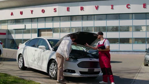 Mechanic inspecting vehicle performance logs on laptop while checking engine, 스톡 동영상 312515749