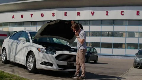 Mechanic inspecting vehicle systems at open car hood, utilizing computer Stock Footage 312517703