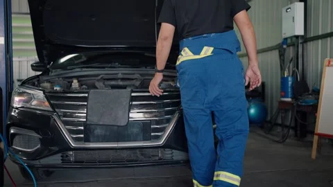Mechanic inspects engine bay in garage Stockbeeldmateriaal 345031775