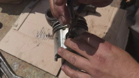 Mechanic installing circlip on engine piston Stock Footage 338411107