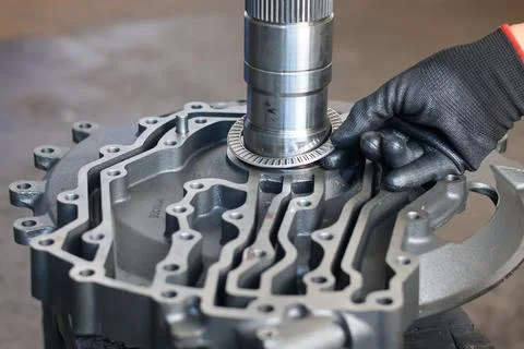 Mechanic installing needle roller bearing onto transmission front support. Stock Photos