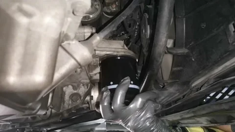 The mechanic is installing a new oil filter on the bottom of the car engine Stock Footage 132865382