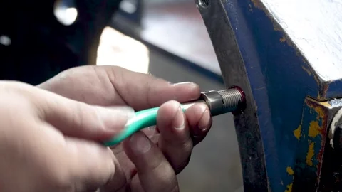 A mechanic installs a thread repair insert into a metallic machine housing. Stock-Footage 346790843