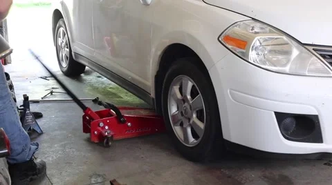 Mechanic jacks up car Stock Footage 64937306