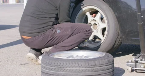 Mechanic jacks up drift car to remove wheel with flat tire Stock Footage 172172434