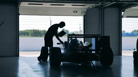 A mechanic with a laptop is checking a racing car Stock Footage 162877858