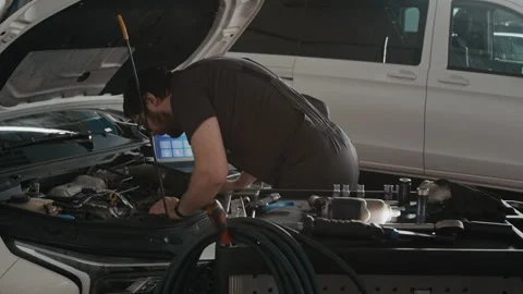 Mechanic with Laptop Performing Diagnostic Work on Car Engine Stock Footage 329410403
