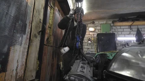Mechanic lifting car engine with chain pulley in garage 库存影片 304119155