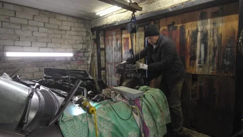 Mechanic lifting car engine with crane in garage Stock Footage 304119074