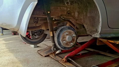 Mechanic lifts a car in a garage using a hydraulic jack, showcasing the process Stock Footage 294308096