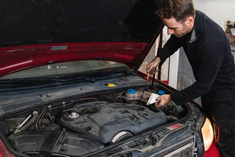 Mechanic looking at oil level in the engine of the car. Concept of automobile Stock Photos