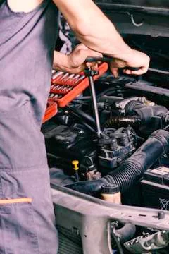 Mechanic looking at a red tool case tightening a nut. Stock Photos