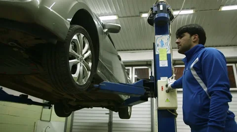 Mechanic lowers the machine holding the button lift Stock Footage 62481521