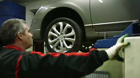 Mechanic lowers the machine holding the button lift Stock Footage 62520869