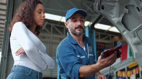 Mechanic man checking engine oil level to woman customer at repair garage. Stock-Footage 157626043