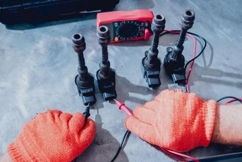 Mechanic man with digital multimeter testing ignition coil Stock Photos