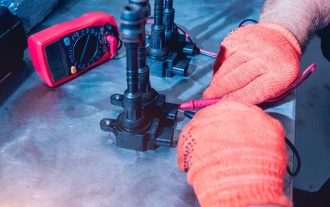 Mechanic man with digital multimeter testing ignition coil Stock Photos