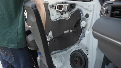 Mechanic man installing a door panel after repairing car speaker Stock Footage 171658067