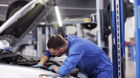 Mechanic man with lamp repairing car at workshop 43 Stock Footage
