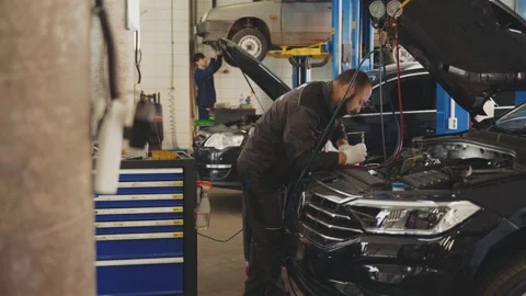 Mechanic man with lamp working at workshop in car service,  car repair and Stock Footage 281580694