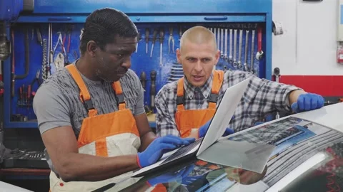 Mechanic man manager with worker in a workshop checks the electronics of the car Stock Footage 249977924