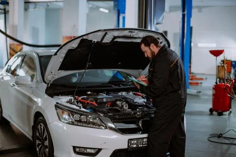 Mechanic man in a uniform write the problem of the car in a map in the modern Stock Photos