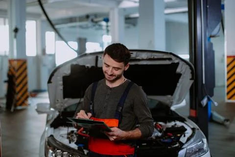 Mechanic man in a uniform write the problem of the car in a map in the modern Foto stock