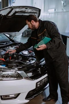 Mechanic man in a uniform write the problem of the car in a map in the modern Stock Photos